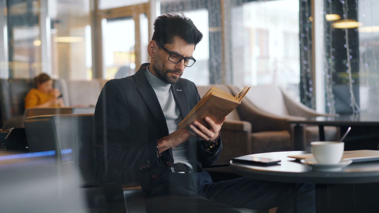 Businessman reading in a modern coffee shop, enjoying a peaceful break.
